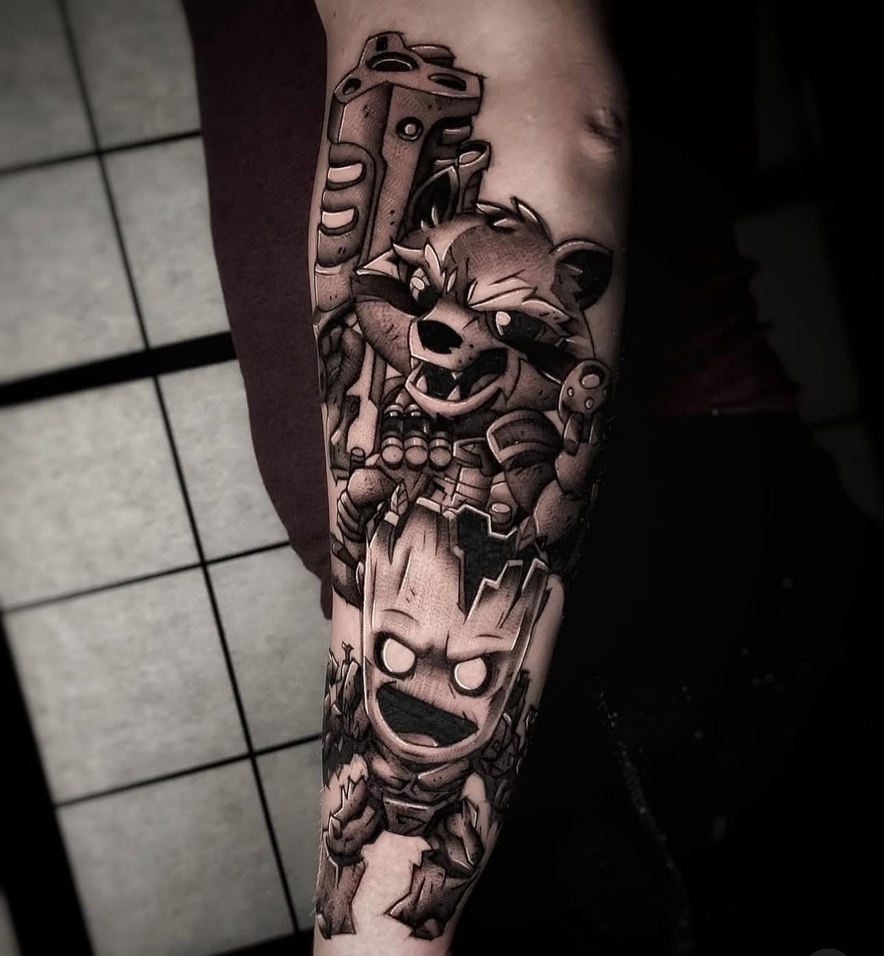 Schwarz-graues Comic-Tattoo mit Guardians-Figuren auf dem Unterarm bei Omilian Tattoo