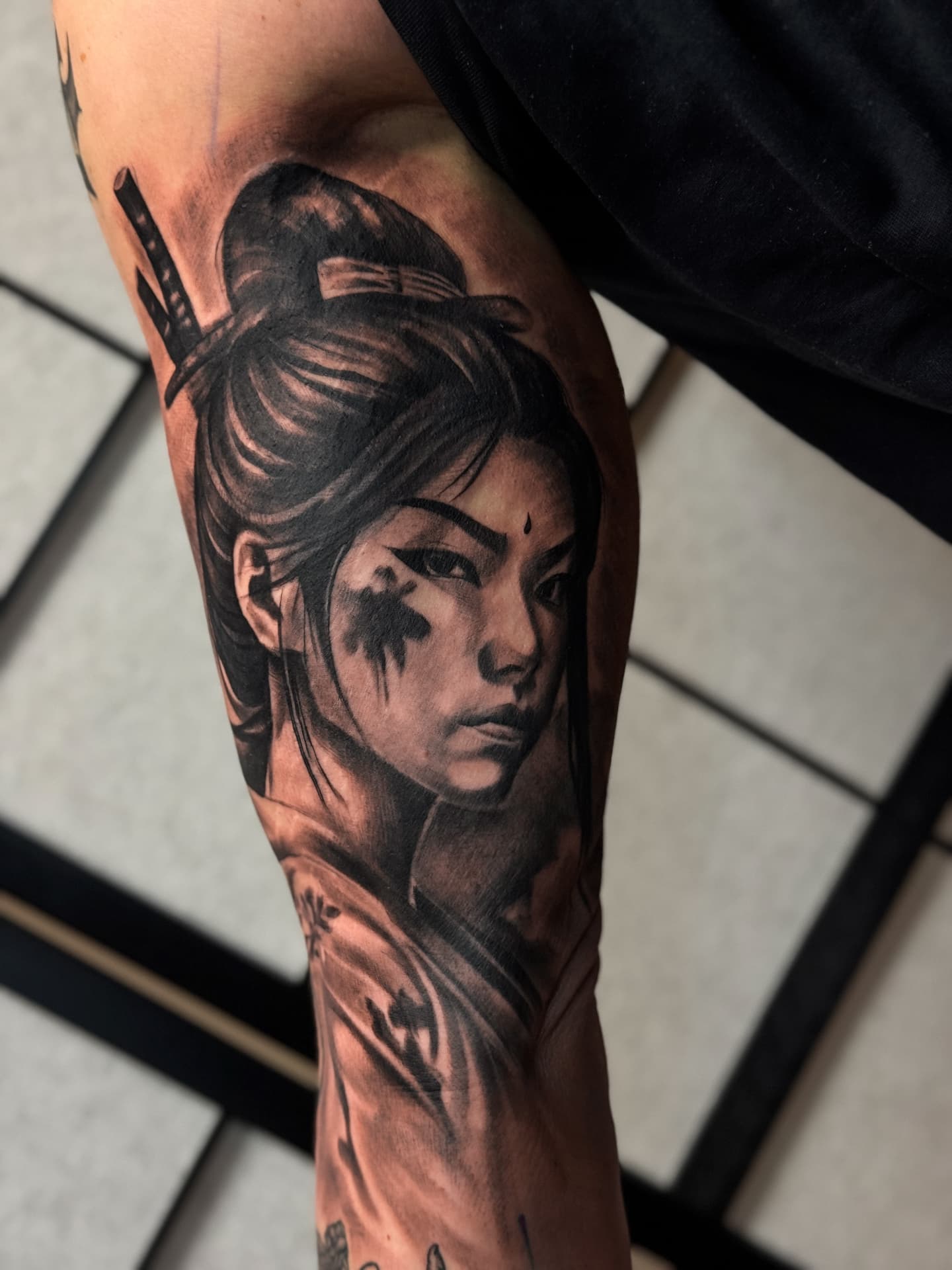 Realistic Samurai-Portrait-Tattoo in Schwarz-Grau auf dem Oberarm bei Kiel