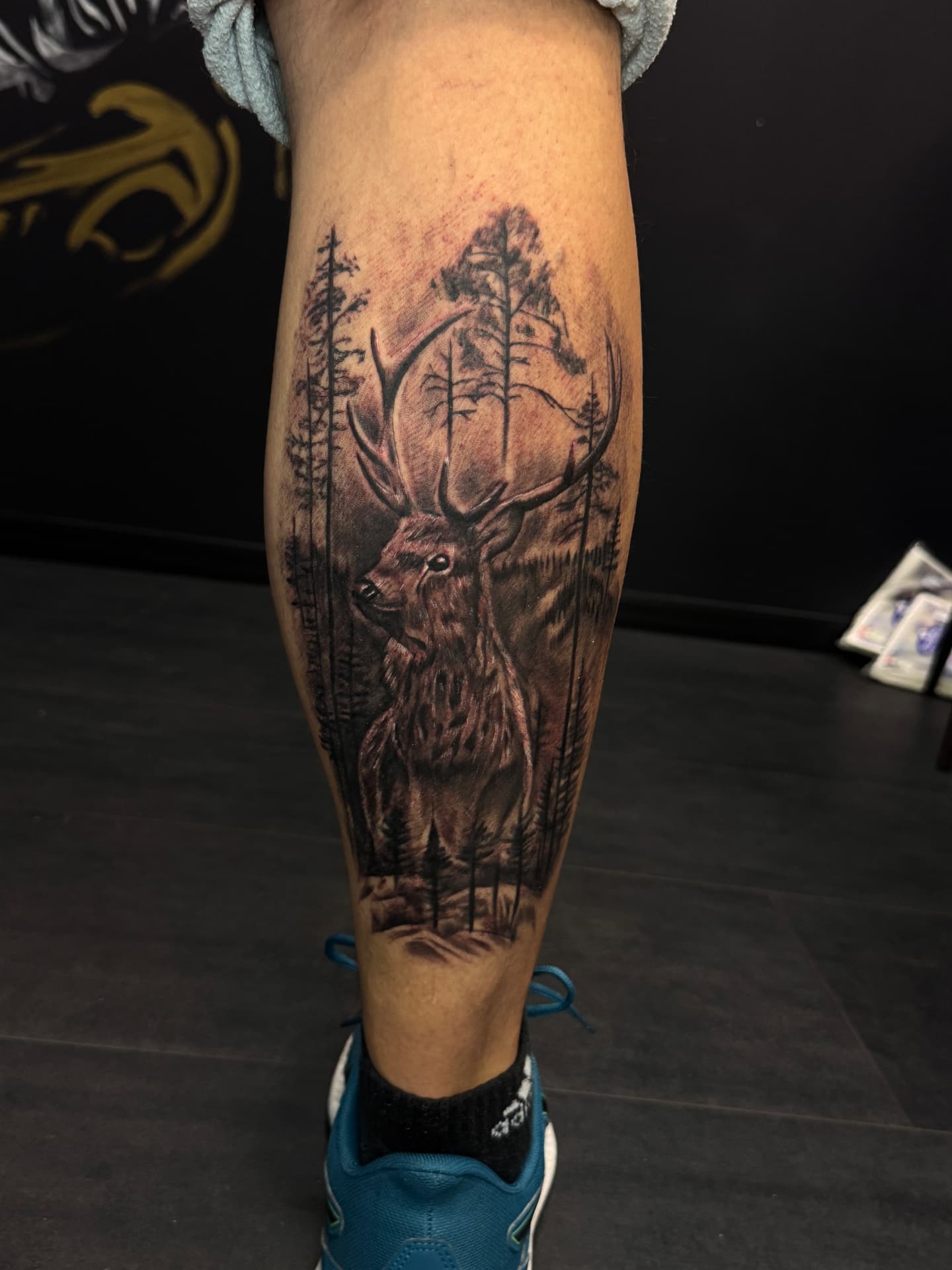 Realistisches Hirsch-und-Wald-Tattoo auf der Wade von Omilian Tattoo in Laboe