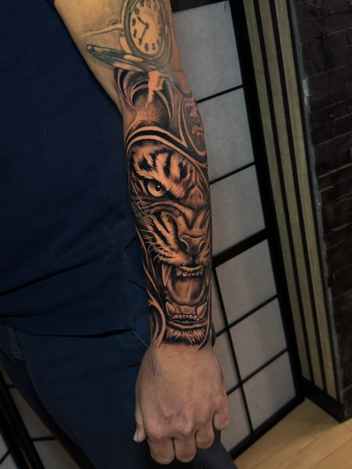 Realistisches Tiger-Tattoo mit Uhr auf dem Unterarm von Omilian Tattoo bei Kiel